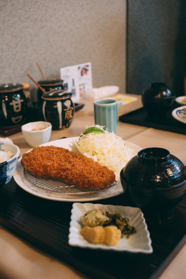 A serving of tonkatsu, with grated cabbage and pickled vegetables on the side.