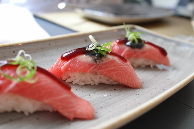 Three pieces of tuna sushi served on a platter.