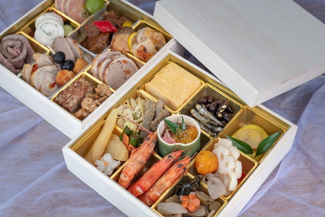 Two bento boxes with an assortment of Japanese dishes. 