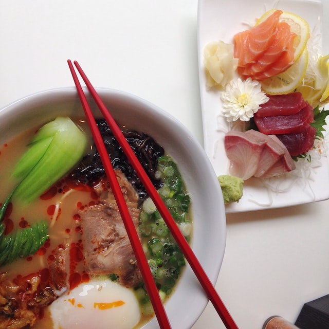 A bowl of ramen with an assortment of sashimi slices on the side.