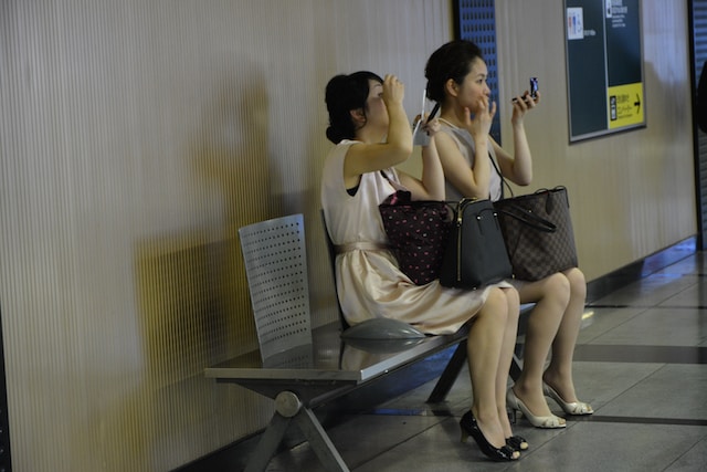 Two young Japanese women putting on makeup