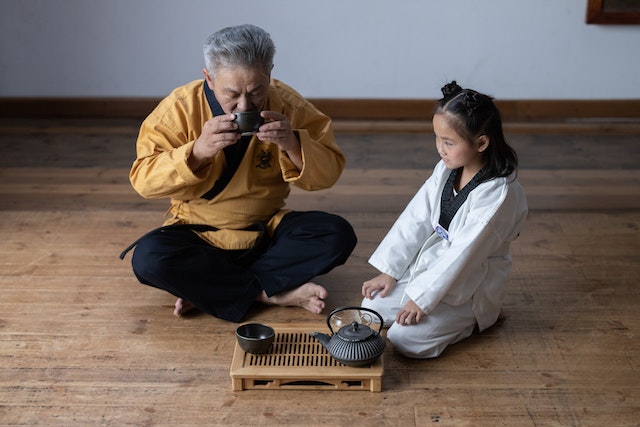 An old man with his grand daughter having tea