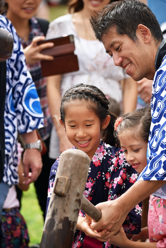 Man demonstrating how to use a wooden mallet for pounding cooked sticky rice at a festival