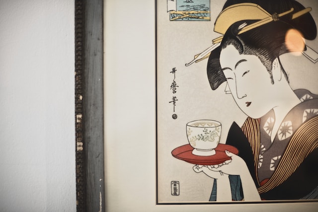 Woodblock print depicting a woman in a kimono holding a red plate with a cup of tea on top