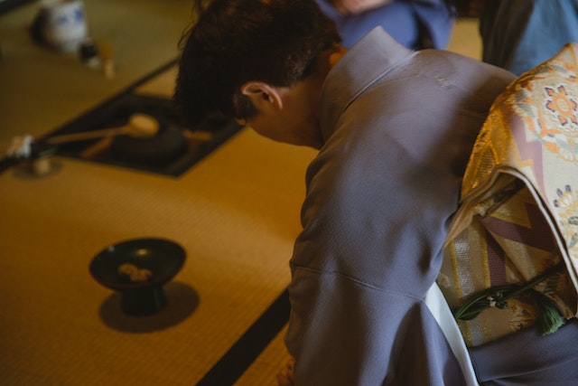 Person wearing a kimono bowing during a tea ceremony