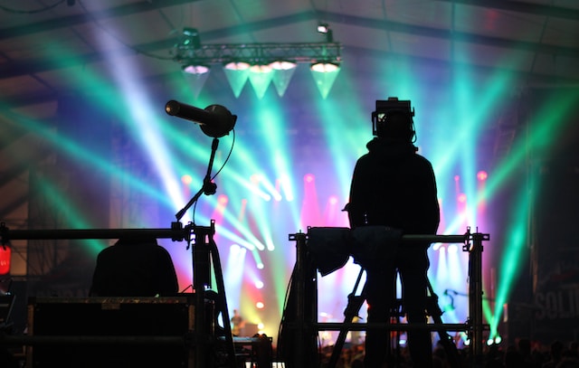 A crew stands facing the stage during a concert