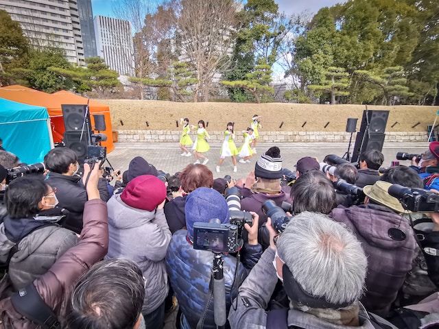 Photographers flock around a group of idols performing on the street